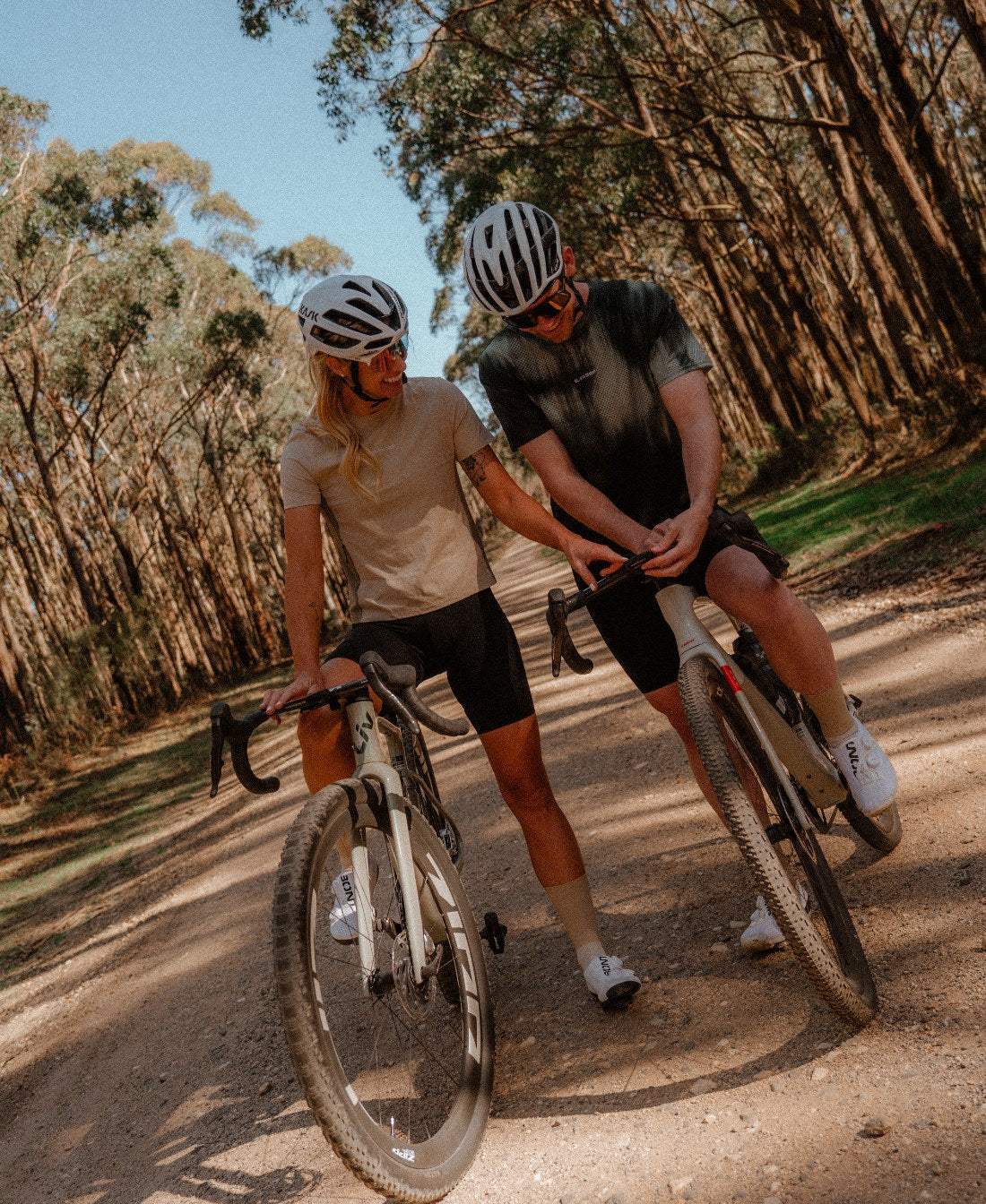 Two riders on a forest gravel road in the Enduro Tee and the Enduro Mesh Tee